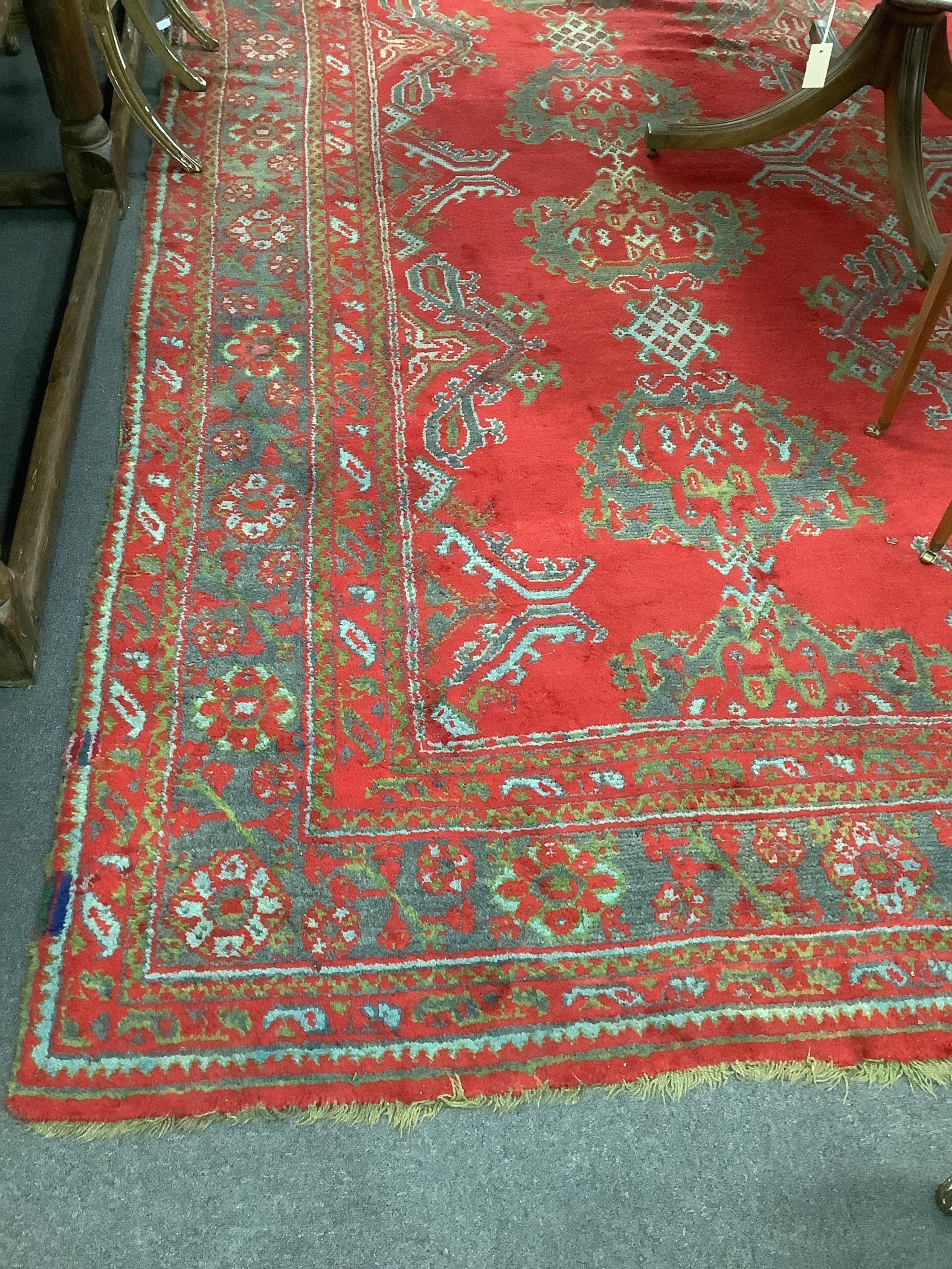 A large Turkish carpet, with triple row of stylised medallions on a red ground, multi bordered, 413 x 345cm. Condition